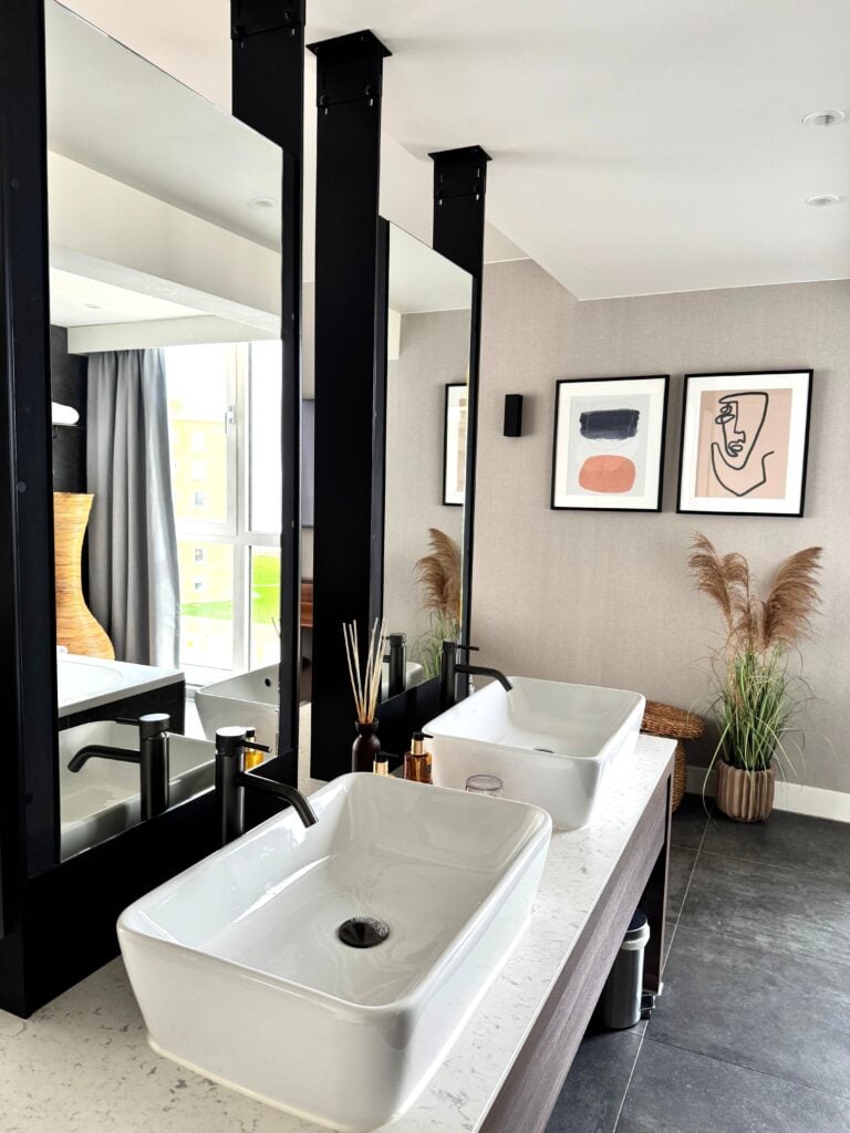Elegant bathroom in The Hague with a modern, minimalist design featuring dual sinks and artistic decor. This article helps you in creating a bathroom that feels as good as it looks.