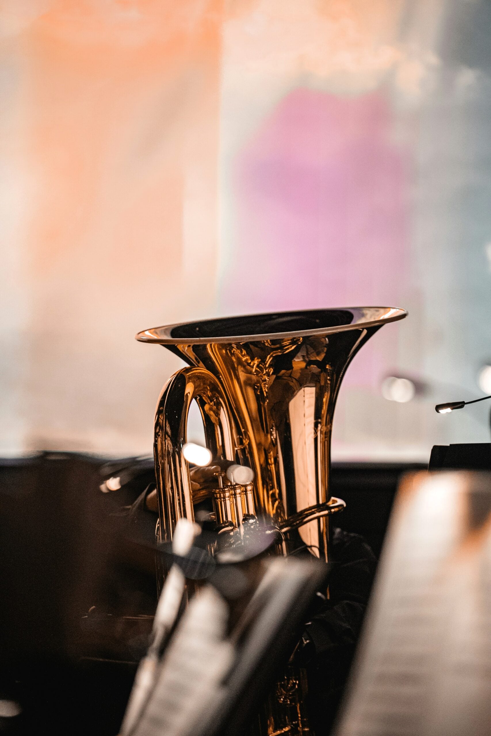 A tuba sits on its own amongst sheet music and stands. This article shares why tubas might be the best instrument choice your kid ever makes.