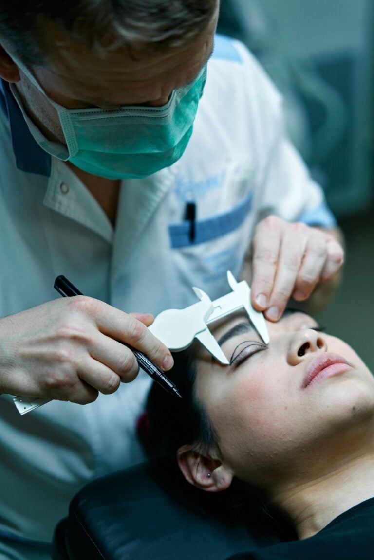 Surgeon measuring patient's eyelid before cosmetic surgery in medical clinic setting. This article covers the best plastic surgery clinics in Toronto and across Canada.
