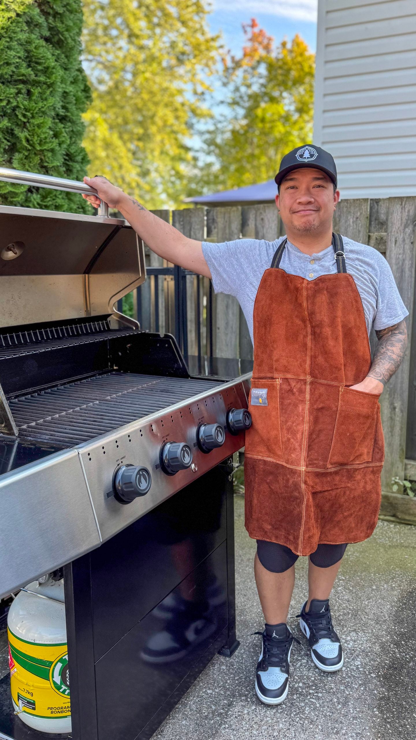 Darasak stands in front of his bbq with the Outset Apron on.