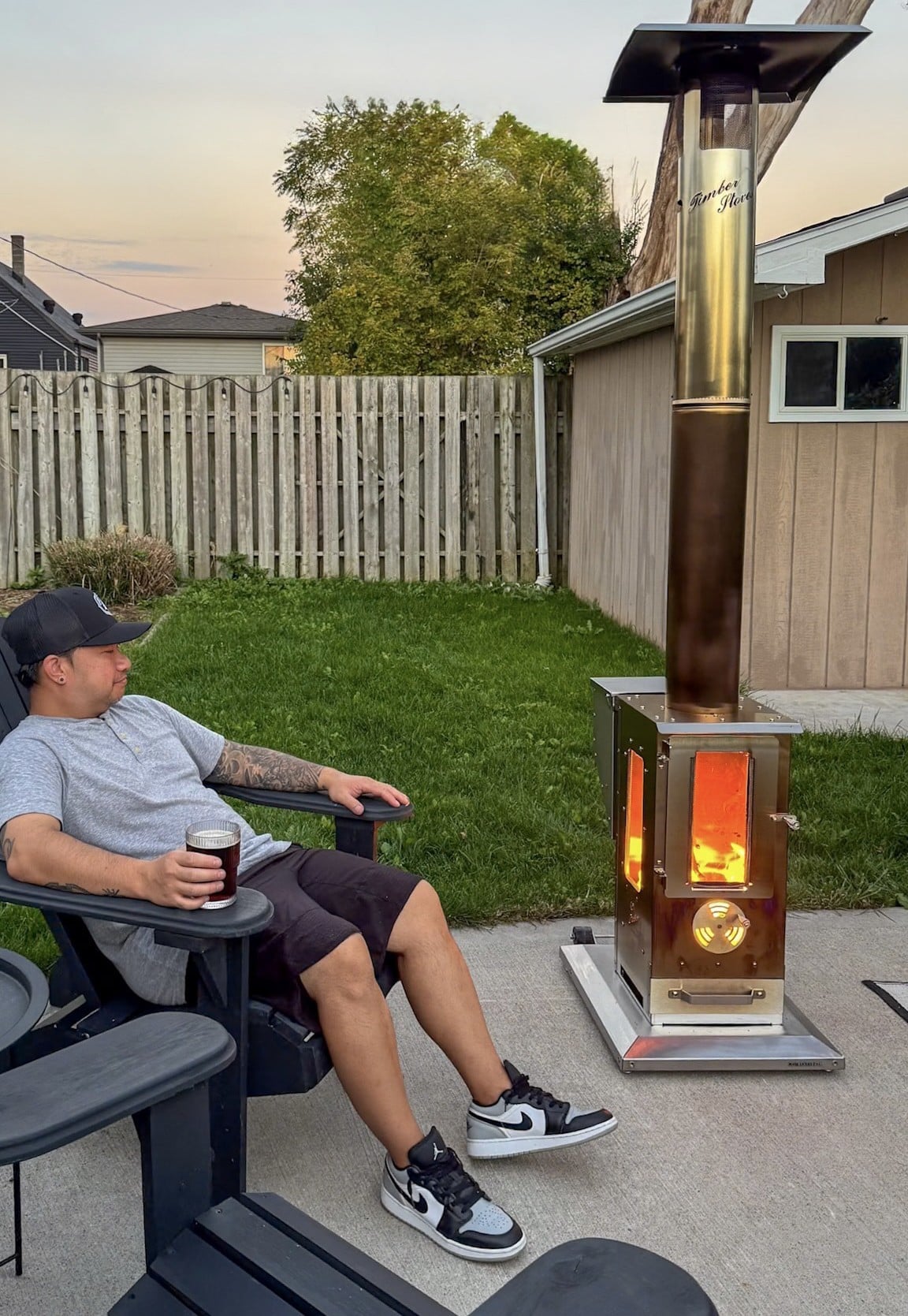 Darasak sits with in a chair with a dark beer and enjoys the heat from the Timber Stoves 'Big Timber'.