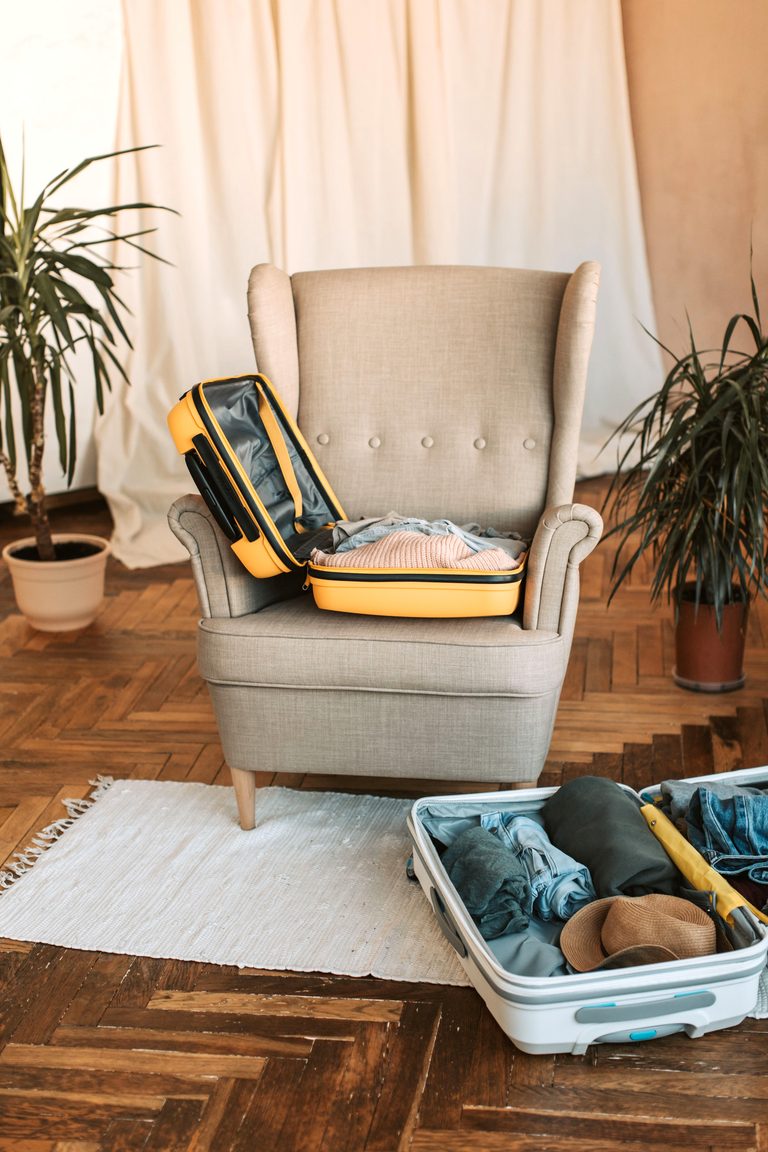 A comfortable chair with open suitcases beside indoor plants, ready for travel preparation. This article shares the strategic architecture of travel planning.