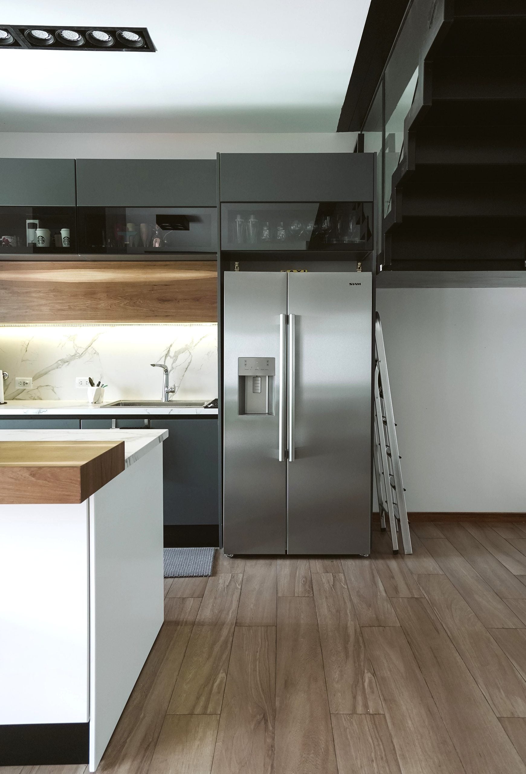 Contemporary kitchen interior featuring stainless steel fridge and marble top in a minimalist design. This article covers how to choose reliable appliance repair services.