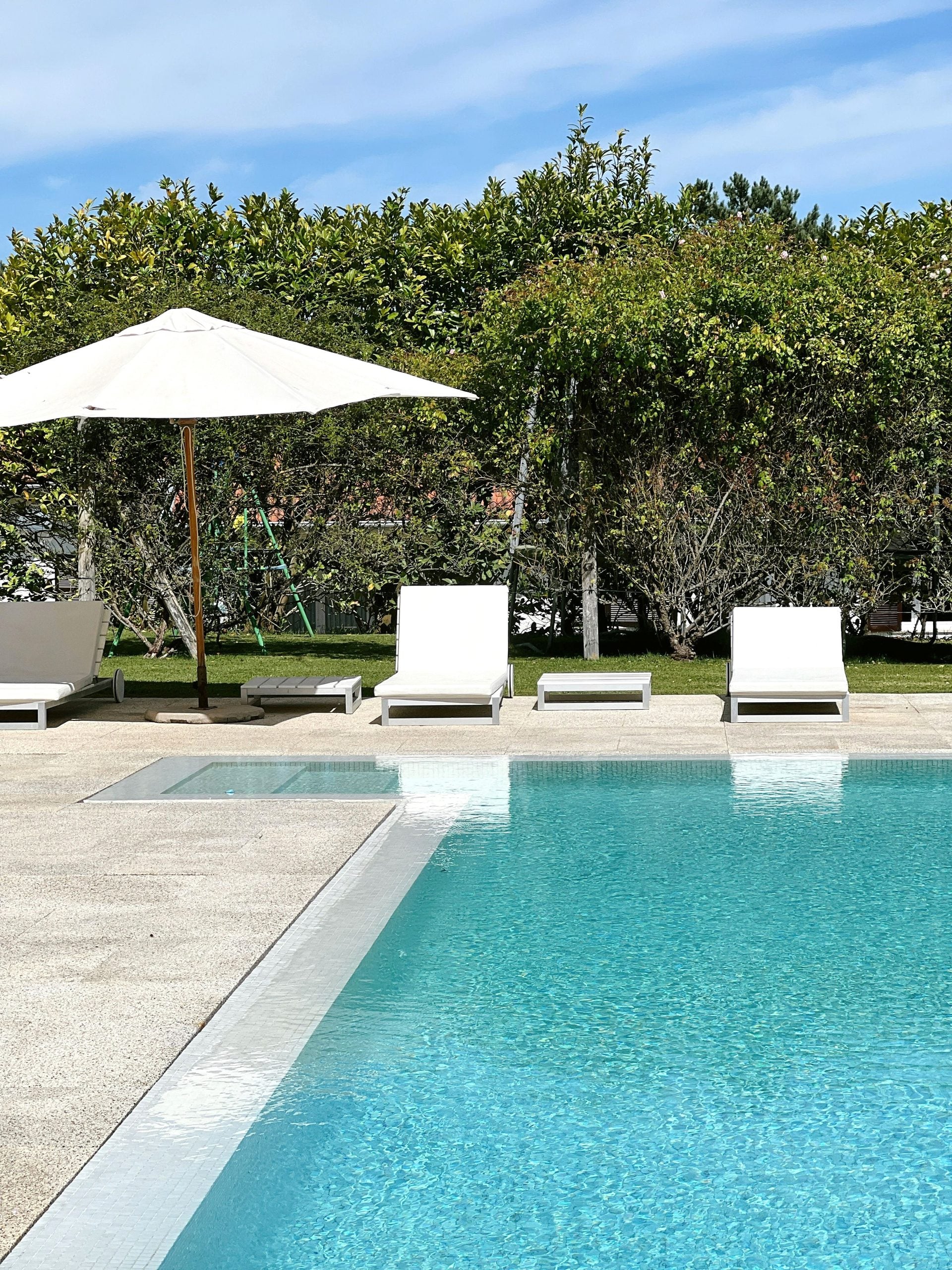 Experience ultimate relaxation at a tropical poolside with sun loungers and umbrellas. This article shares how to create your dream backyard with custom pool construction and design.
