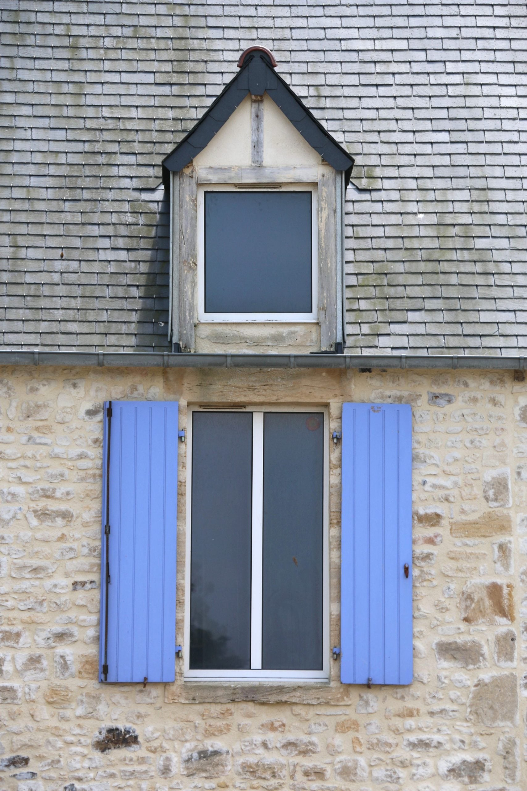 Charming stone wall facade with blue shutters, featuring classic architecture.
This article shares when to repair a roof or replace it.